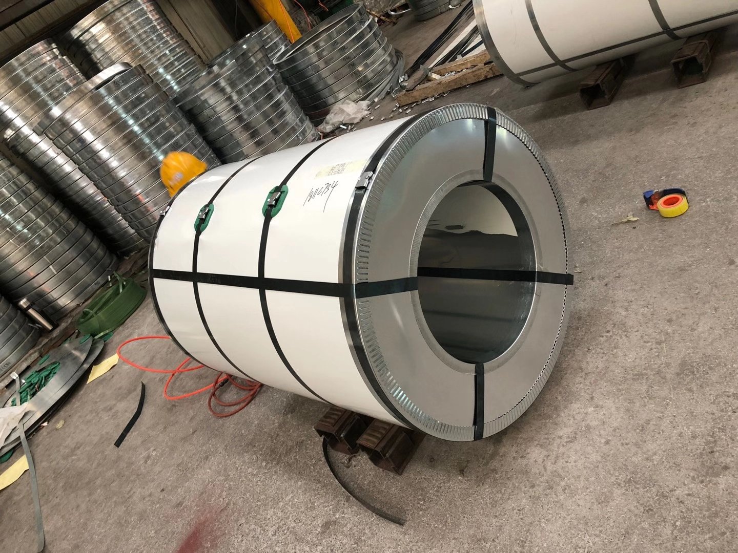 Painted steel coil secured with straps in a workshop